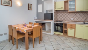 Une cuisine de taille réduite comprenant une table à manger, des chaises, un téléviseur et une cuisinière.