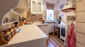 A kitchen with white cabinets, a central island, a window with curtains, a radiator, and a stove. - casa dei fiori by Interhome (Mergozzo (Lago di Mergozzo))