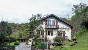 Una casa de dos pisos con un muro de piedra y un balcón.