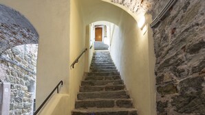 A stone staircase with a handrail, leading to a wooden door at the top.
