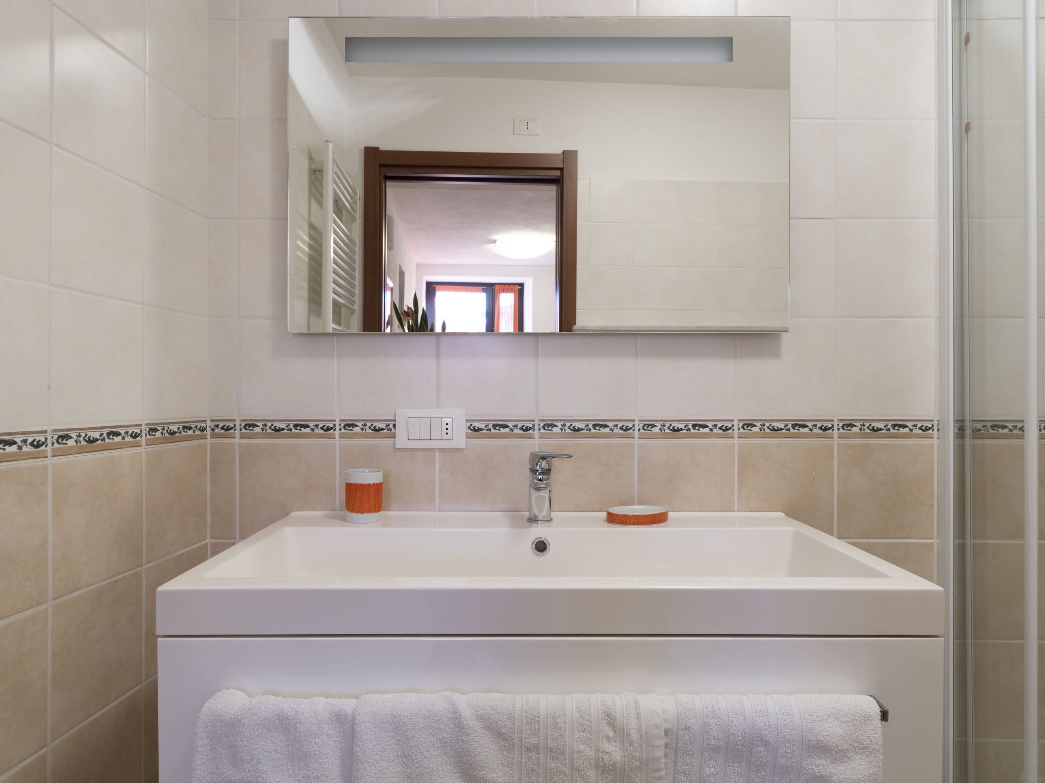 A bathroom with a white sink, a mirror above it, and a towel rack below.