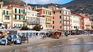 Une ville côtière aux bâtiments aux couleurs vives, avec une plage et un paysage montagneux en arrière-plan.