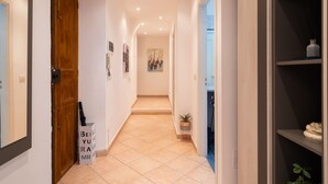 Un couloir avec une porte en bois, une pancarte et un tableau accroché au mur.