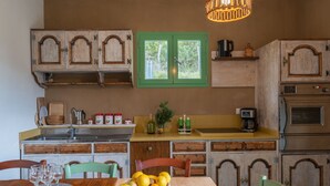 A kitchen with wooden cabinets, a green door, and a dining table with chairs. - Oasi Colorata by Interhome (Stellanello)