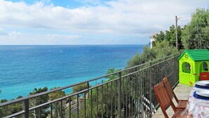 A balcony with a view of the sea, a small green playhouse, and a table with chairs. - La Perla del Mediterraneo by Interhome (Cervo)