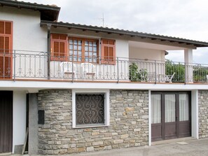 Ein zweistöckiges Gebäude mit Balkon, Steinhausfassade und einem Metallgitter.