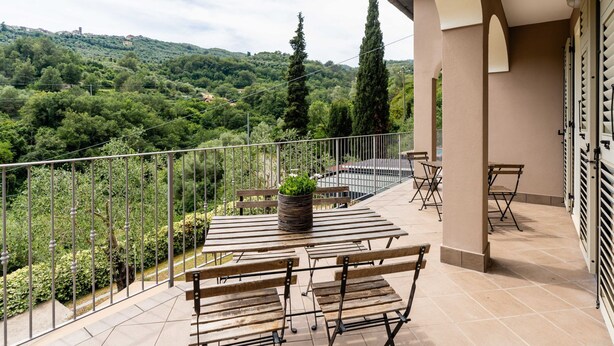 A balcony with outdoor seating, a potted plant, and a view of a lush, green hillside. - Casa Mimosa by Interhome (Pontedassio)