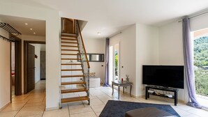 A modern living room with a staircase, a flat-screen TV, and a balcony with a view. - Casa Mimosa by Interhome (Pontedassio)