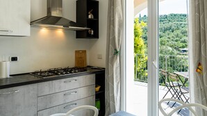 A modern kitchen with a gas stove, cabinets, and a view of a balcony with outdoor furniture. - Casa Mimosa by Interhome (Pontedassio)