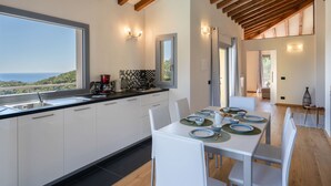 A modern kitchen with white cabinets, a black countertop, and a view of the sea. - Bellaria (VLO190) by Interhome (Valloria)