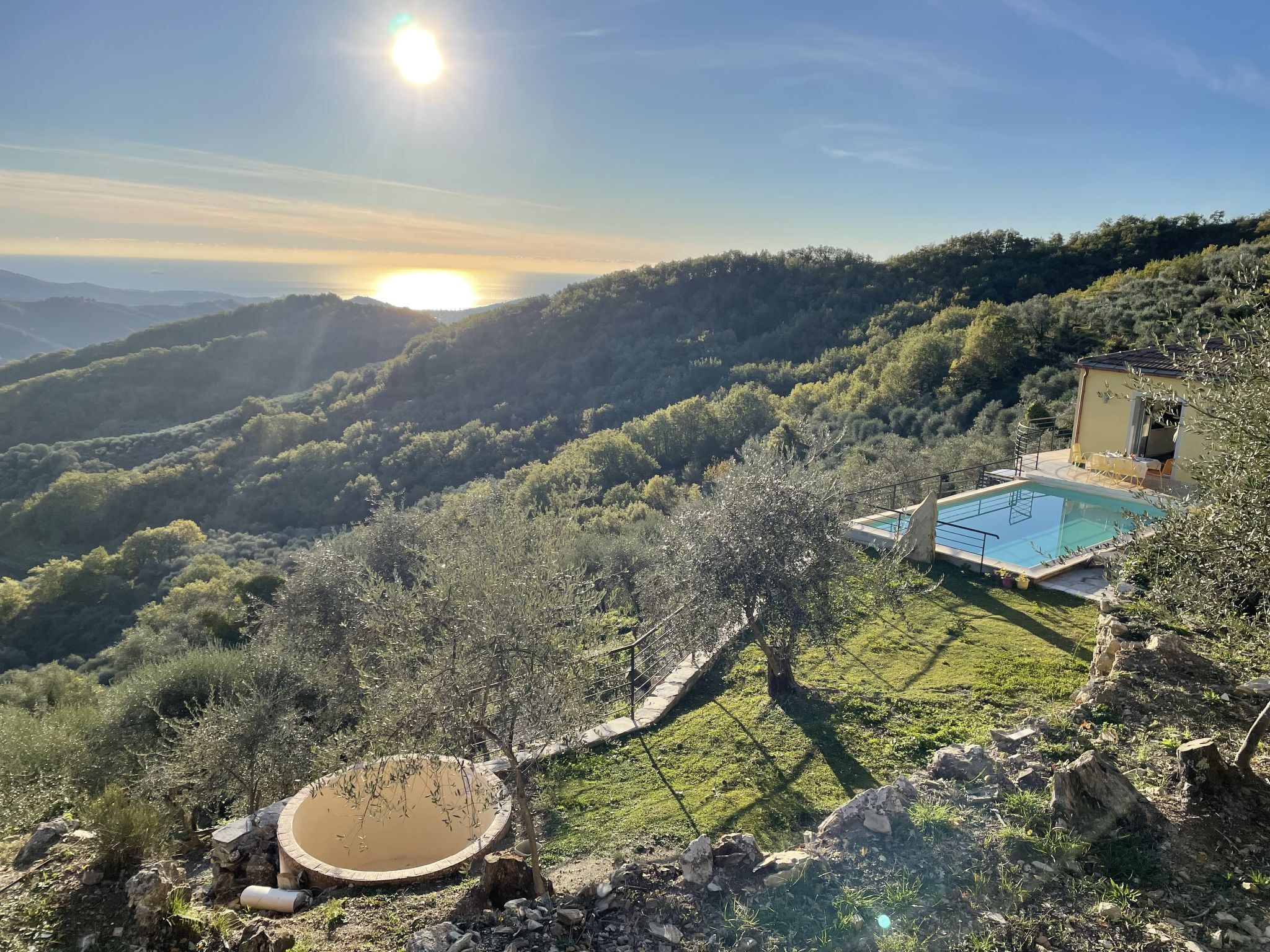 Ein Pool mit Blick auf eine gebirgige Landschaft, ein kleines Gebäude mit Balkon und eine runde Steinarchitektur.