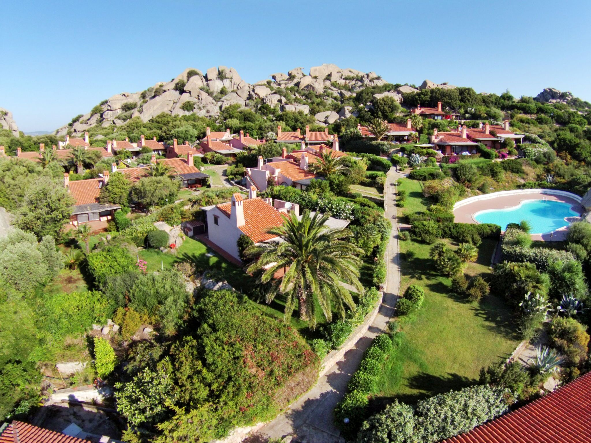 A residential area with houses, a swimming pool, and a mountainous backdrop.