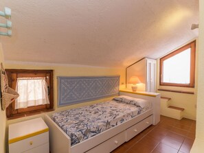A bedroom with a bed, a nightstand, a window, and a door. - Le Rocce (PAU219) by Interhome (Palau)