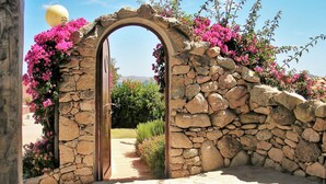 A stone archway with pink flowers, leading to a pathway. - Vacation home Anita by Interhome (Palau)