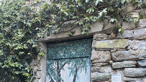 Un mur de pierre avec une porte ornée d’une fresque représentant un arbre.