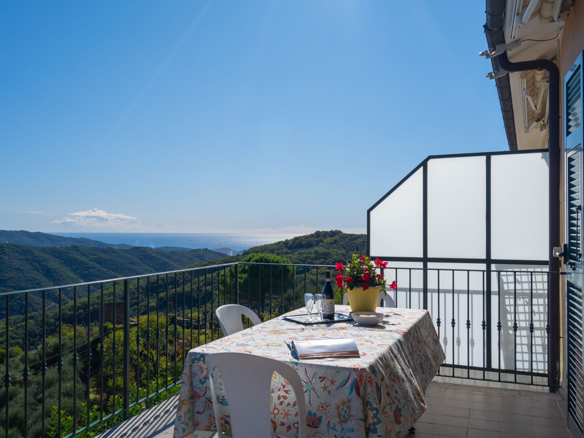 Ein Balkon mit Tisch für zwei Personen, mit Blick auf eine gebirgige Landschaft.