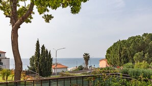 Un quartier résidentiel situé sur la côte, offrant une vue sur la mer, doté d’un jardin clôturé et de maisons aux toits recouverts de tuiles rouges.