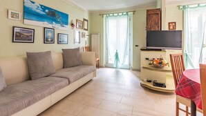 Un salon comprenant un canapé, un téléviseur et un coin repas avec une table et des chaises.