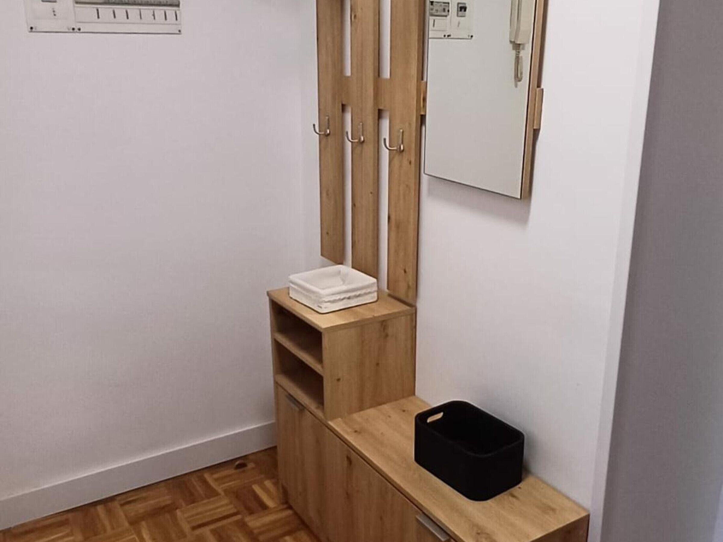Un banyet petit amb un lavabo de fusta, un mirall i un paperer negre.