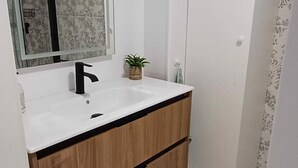 Une salle de bain avec un lavabo blanc, un robinet noir et des meubles en bois.
