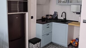 Une cuisine compacte dotée d’un four encastré, d’un évier et d’un petit plan de travail.