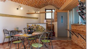Un comedor con techo de ladrillo, pared de ladrillo con diseño de hojas y una estantería para vinos con botellas.