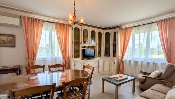 A dining area with a wooden table and chairs, a television, and a cabinet with glass doors. - Renovated Townhouse in Argy: Private Garden, Game Room, Near Château and ZooParc de Beauval (Argy)