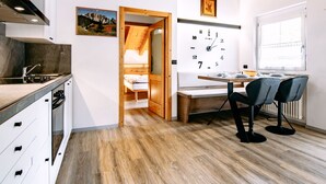 Eine moderne Küche mit Holzboden, einem Essbereich mit Holztisch und -stühlen sowie einer Wanduhr.