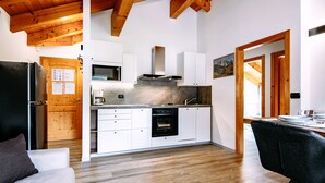 Eine moderne Küche mit weißen Schränken, einem schwarzen Kühlschrank und einer Holzziel.