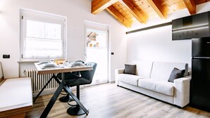 Eine moderne Küche mit Essbereich, weißen Wänden, Holzbalken an der Decke und einem weißen Sofa.