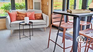 Une pièce chaleureuse avec un canapé gris, des coussins orange, une petite table ronde et une chaise.