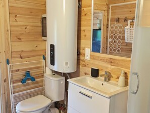 A compact bathroom with a toilet, sink, and a white heater. - Cozy Chalet Near Laval: Nature, Activities & Family-Friendly Sleeps 4 (Saint-Berthevin)