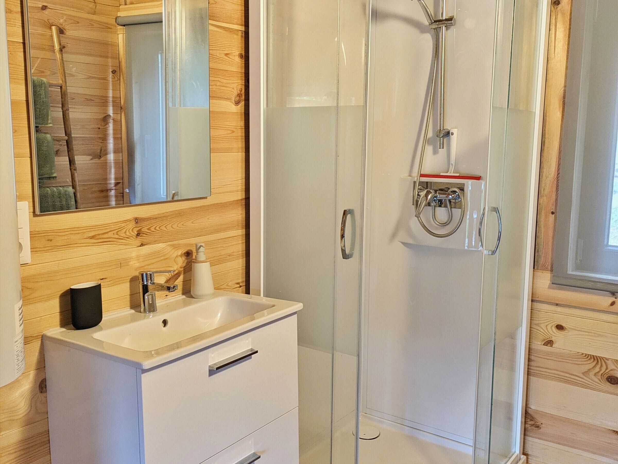 A modern bathroom with a glass shower enclosure, a wooden vanity, and a mirror.