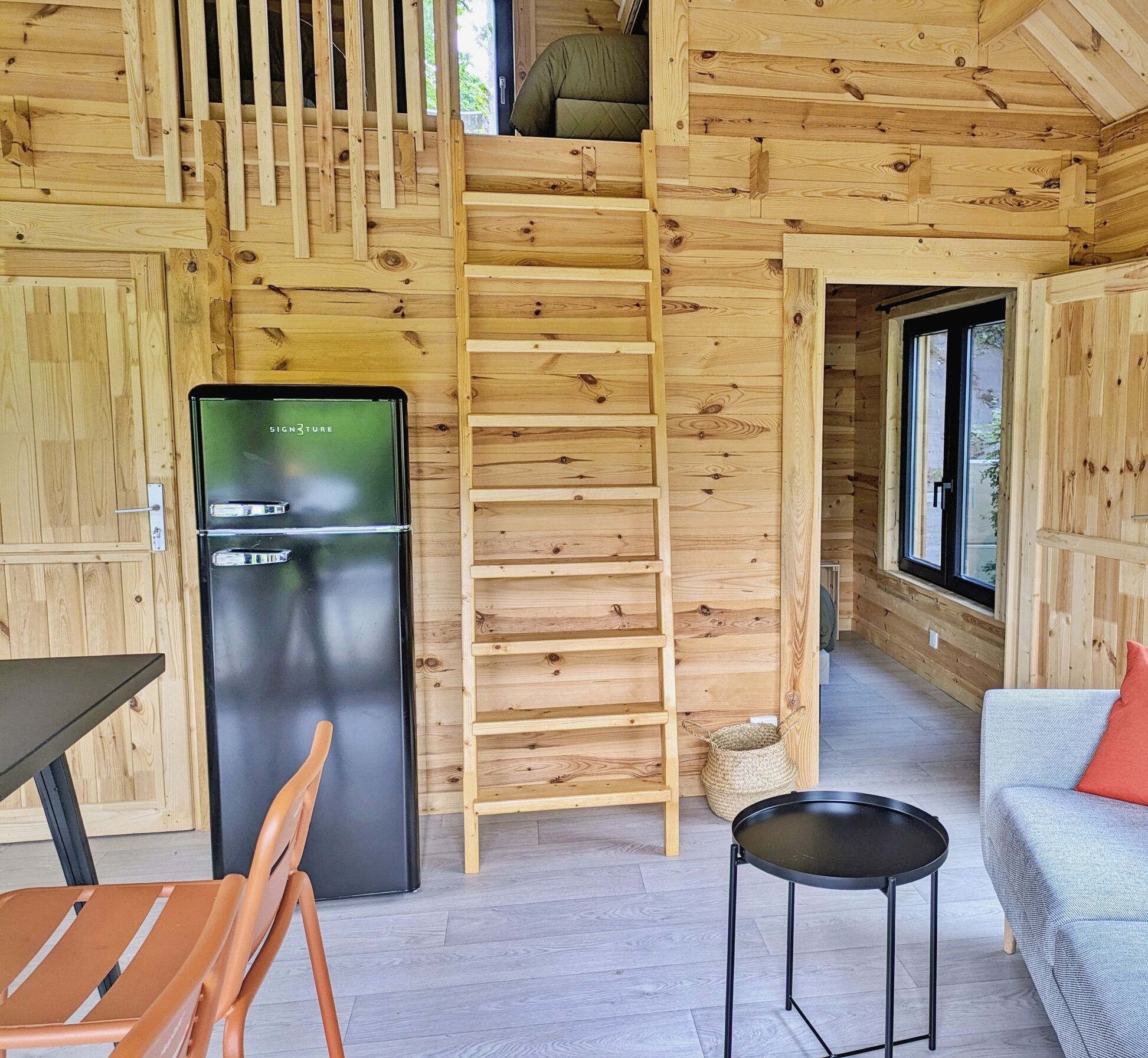 Eine gemütliche Holzhütte mit Küchenzeile, Essbereich und einer Couch mit Kissen.