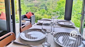 Un comedor con una mesa lista para cuatro personas, con vistas a un paisaje boscoso.