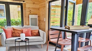 Una habitación acogedora con un sofá gris, cojines naranjas, una mesita redonda y una silla.