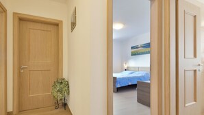 Ein Flur, der in ein Schlafzimmer mit einem Bett, einem Nachttisch und einem Wandbild führt.