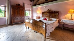 A bedroom with a wooden bed, a nightstand, a lamp, a wardrobe, and a window with curtains.