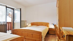 A bedroom with a wooden bed, a wooden wardrobe, and a desk with a chair. - Bernard by Interhome (Campitello)