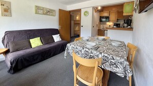A compact living space with a sofa, dining table, chairs, and a kitchenette. - Cozy 2-Room Cabin Apartment in Praz Sur Arly, Close to Ski Lifts, Sleeps 5, Parking Included (Praz-sur-Arly)