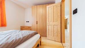 Une chambre à coucher avec un lit, une armoire en bois et une porte.