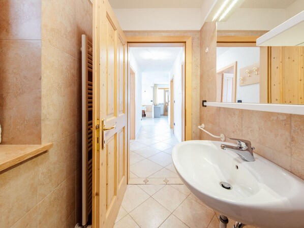 Une salle de bain moderne avec un grand lavabo, une porte en bois et un sol carrelé.