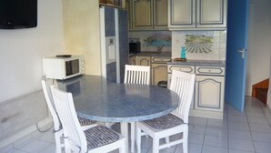 Una cocina con una mesa redonda y sillas blancas, un microondas y armarios.