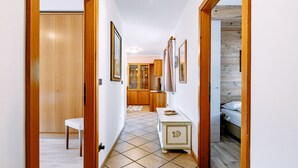 Um corredor com portas de madeira, um banco branco, uma toucador com espelho e uma cama com cabeceira de madeira.