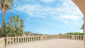 Terraço no telhado com espreguiçadeiras, guarda-corpo decorativo e vista para uma colina.