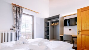 A hotel room with a bed, a desk, a wardrobe, and a television. - Apartment Carmen by Interhome (Soraga di Fassa)