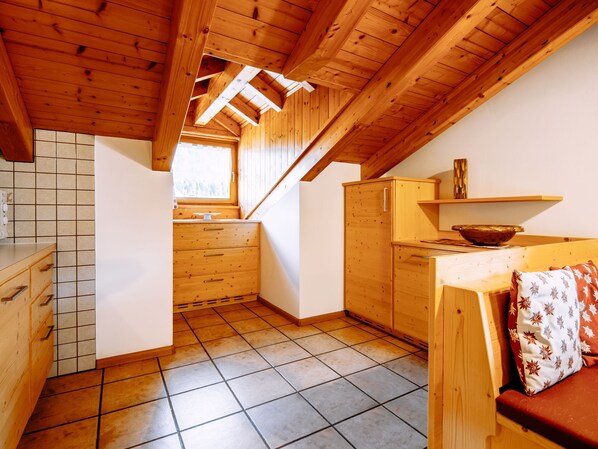 Una cocina compacta con armarios de madera, piso de baldosas y una ventana que proporciona luz natural.