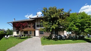 Un edificio su due piani con vialetto lastricato che conduce a una zona salotto esterna coperta.