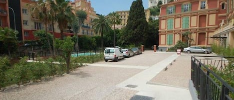 Une rue résidentielle bordée de voitures garées, de palmiers et d’immeubles à plusieurs étages dotés de balcons.