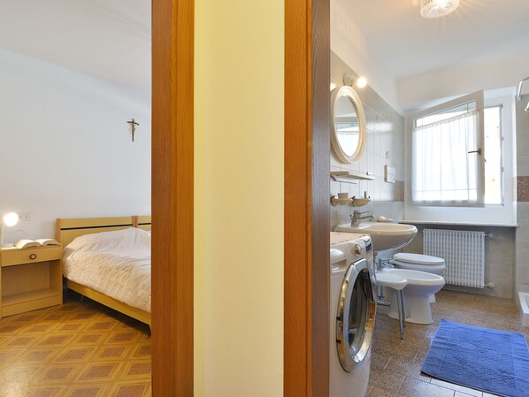 Een slaapkamer met een bed, nachtkastje en een klein tafeltje.